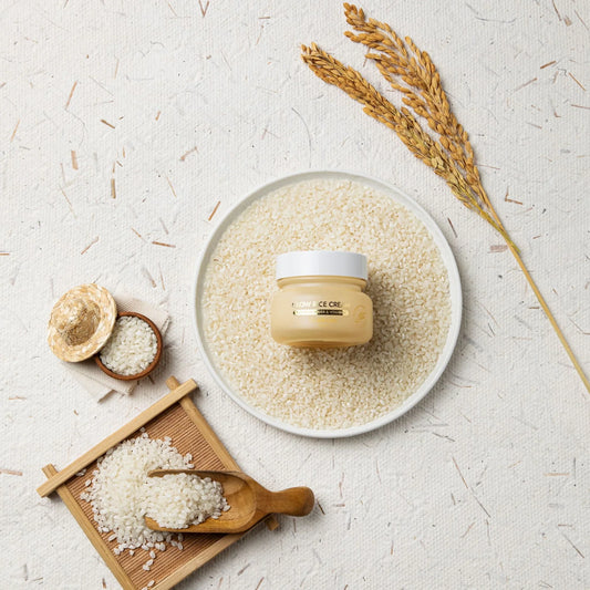 Glow Rice Cream with rice grains, rice stalks, and wooden spoon on textured background for K-Beauty skincare