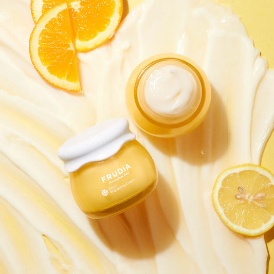 Frudia Citrus Brightening Cream vegan skincare jar with white lid on yellow background with citrus fruits