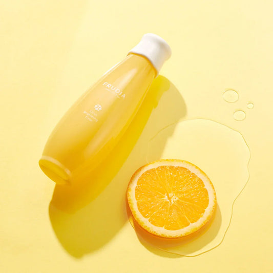 FRUDIA Citrus Brightening Toner with fresh orange slice on sunny yellow background for glowing skin