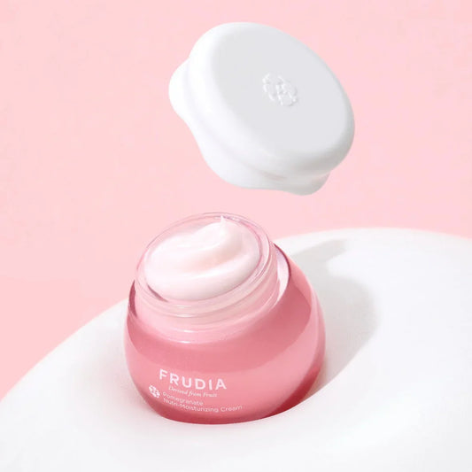 Frudia Pomegranate Nutri-Moisturizing Cream in a pink jar, vegan firming skincare product on white and pink background